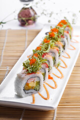 A long porcelain plate of crab roe professor rolls placed on a sushi curtain