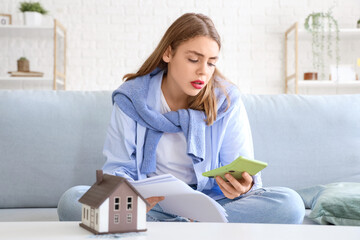 Young woman with calculator and bills at home. Price rise concept