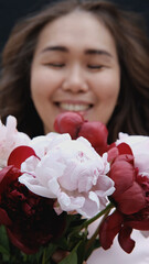 Portrait of a beautiful smiling woman with a bouquet of peonies in her hands. close-up.
