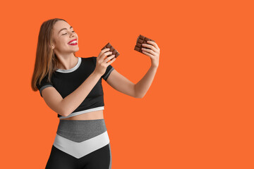 Young woman with chocolate bar on orange background
