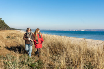 Two women walking on the seashore. Two friends enjoying and spending time together.
