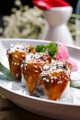 Grilled eel nigiri sushi on a white gooseneck porcelain plate on a stone