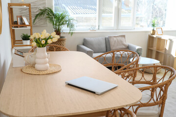 Dining table with tulips and laptop in room