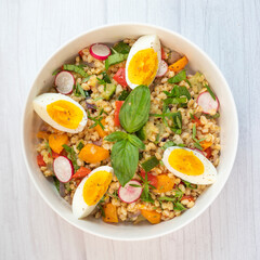 Freshly made spelt salad features roasted zucchini, carrots, onions, red peppers, and basil, topped...