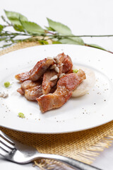 Grilled beef belly in a round white porcelain plate placed on a straw mat