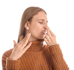 Young woman feeling bad smell on white background