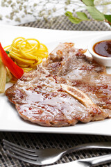 New Zealand T-bone steak in a square porcelain plate on a placemat