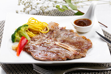 New Zealand T-bone steak in a square porcelain plate on a placemat