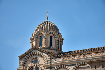 Dome and architectural details of Notre Dame de la Garde in Marseille, France, under a clear blue...