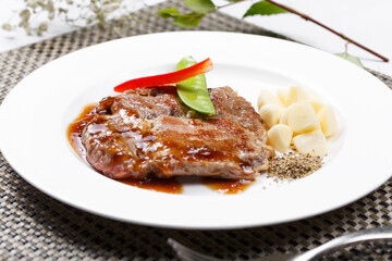 Grilled garlic pork chop with black pepper sauce on a placemat