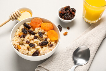 Tasty oatmeal with dried fruit on light background