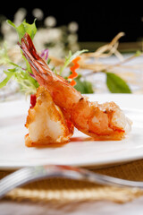 A round white porcelain plate of deep-sea prawns on a straw mat
