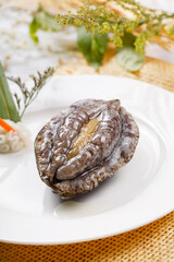 Fresh abalone in a round porcelain plate placed on a straw mat