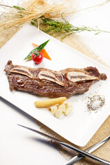 Japanese style iron plate with bone-in steak placed on a straw mat