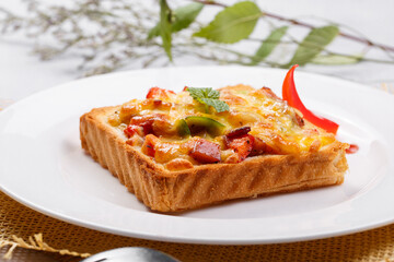 Freshly grilled seafood beef pizza on a white round plate placed on a straw mat