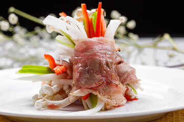 French foie gras beef rolls on a white round plate placed on a straw mat