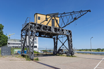 A unique gantry crane with a small wooden cabin, situated in an urban area by the water under a...