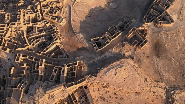 An ancient city made up of stone structures with a sky background. Some of the structures have a roof. The ground is rocky and uneven, with a dusty atmosphere. Location: Tunisia, Gabes , Zraoua.