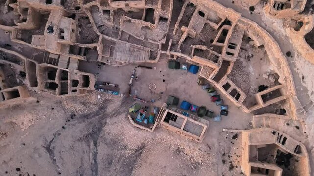 A scene from the ruins of an ancient city with tents set up among the rubble and a mountainous background. Location: Tunisia, Gabes , Zraoua.