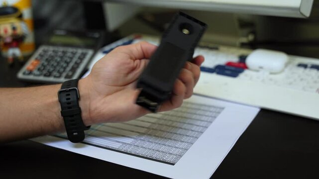 Hand gripping classic black stapler over document stack&mdash;ideal for office, organization, admin, or business tool visuals.