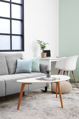 Stylish interior of light living room with sofa, carpet and coffee table