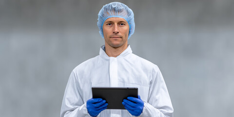 Technician sterile lab blue gloves white coverall hairnet tablet focused expression professional
