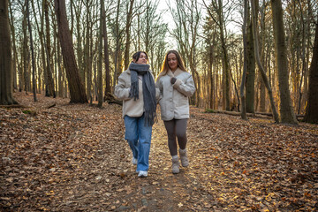 Obraz premium Two female friends on a walk in the forest. Friends walking through the forest. People in nature.
