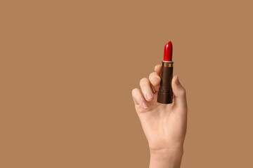 Female hand with red lipstick on brown background