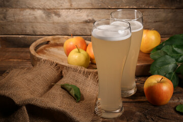 Glasses of fresh apple kvass and tray with fruits on wooden background