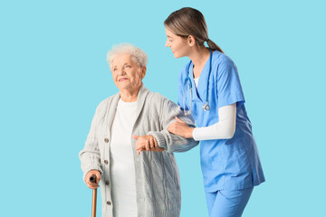 Senior woman with stick and nurse walking on blue background