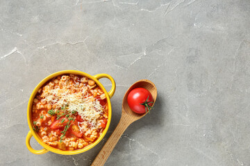 Bowl of pasta fagioli with cheese and thyme on grey background