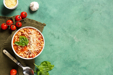Bowl of pasta fagioli with ingredients on green background