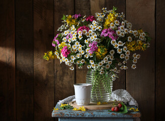 A lush bouquet of summer flowers in a transparent vase is placed on an old blue stool. still life...