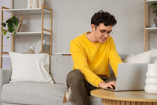 Handsome young man using laptop on table at home