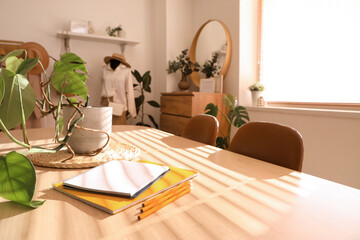 Plant with notebooks on table in clothing store office, closeup