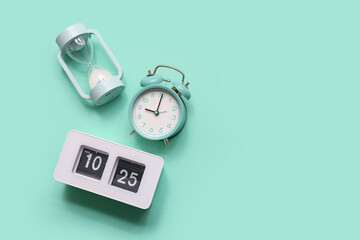 Hourglass with alarm clocks on turquoise background. Concept of evolution