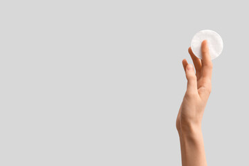 Female hand holding cotton pad on white background