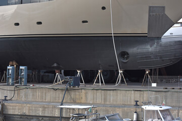 Scafo yacht in dry dock con cavalletti e attrezzatura da cantiere