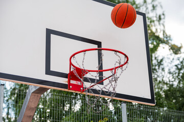 Street basketball action  ball flying toward hoop with metal chain net