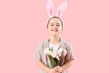 Cute little girl in bunny ears with tulips on pink background. Easter celebration