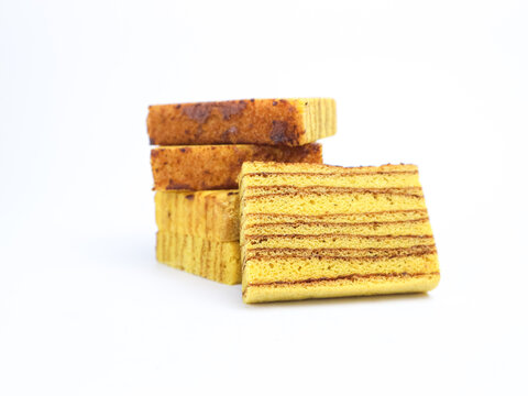 Indonesian layered cake slices (kue lapis legit) stacked on white background. Traditional sweet dessert with rich buttery layers and spiced aroma