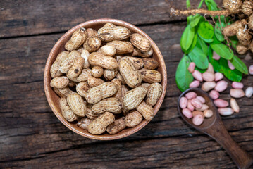 Peanuts in a peel in a wooden bowl. peeled peanut on peanut group on wooden bowl.