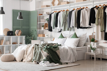Interior of light bedroom with laptop on cozy bed and stylish wardrobe