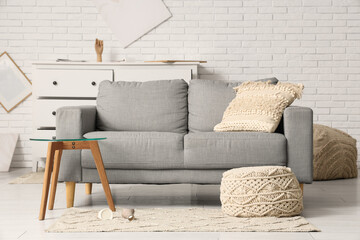 Interior of messy living room with grey sofa and coffee table after earthquake