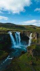 Obraz premium Majestic Waterfall Cascading into a Lush Valley Under a Clear Sky