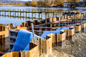 Construction site along a riverbank featuring portable structures and protective vegetation in a...