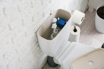 Toilet bowl with removed tank lid and water in light restroom