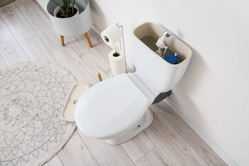 Toilet bowl with removed tank lid and water in light restroom, closeup
