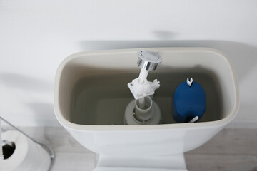 Toilet bowl with removed tank lid and water in light restroom, closeup