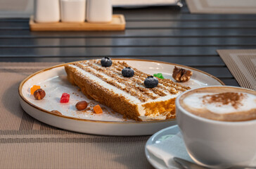 A piece of honey cake on a plate on a table in a sidewalk cafe. 